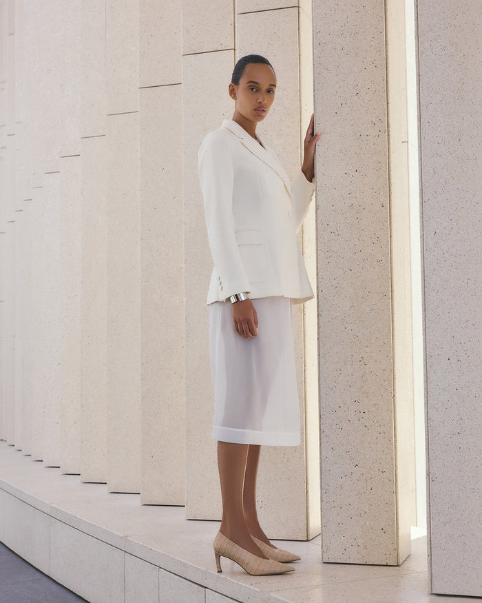 Woman in a white outfit standing between two columns in a minimalistic setting