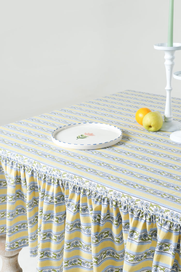 Provence Butter Yellow Ruffled Cotton Tablecloth — close view of the striped cloth and ruffle beside separate tableware; Inner Child