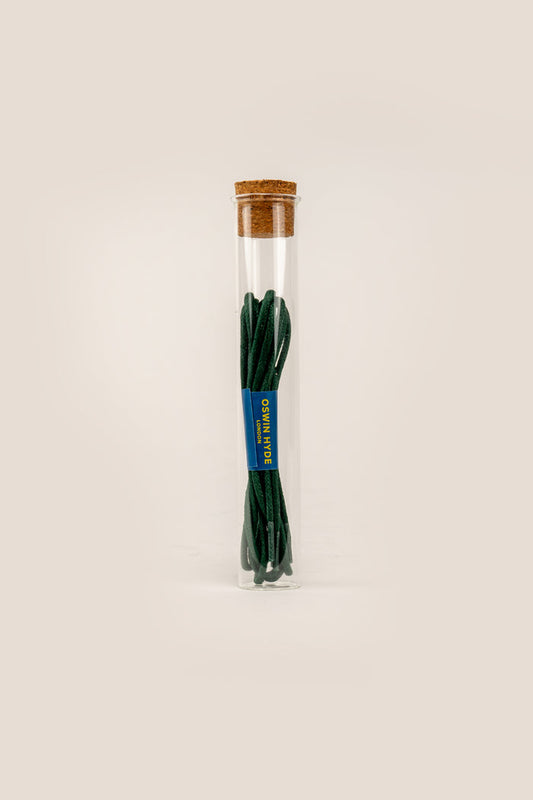 Dark green 2mm round waxed cotton shoe laces by Oswin Hyde, polished with natural beeswax and packaged in a sleek, reusable glass tube.