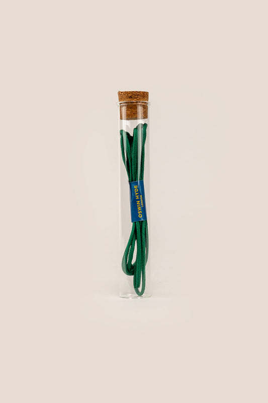 Light green 2mm round waxed cotton shoe laces by Oswin Hyde, beeswax-finished and elegantly packaged in a reusable glass tube.