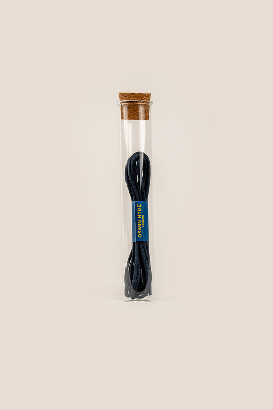 Navy blue 2mm round waxed cotton shoe laces by Oswin Hyde, polished with beeswax and stylishly presented in a clear glass tube.