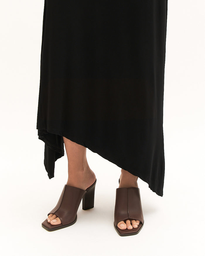 Person wearing brown open-toe sandals with a black dress on a white background